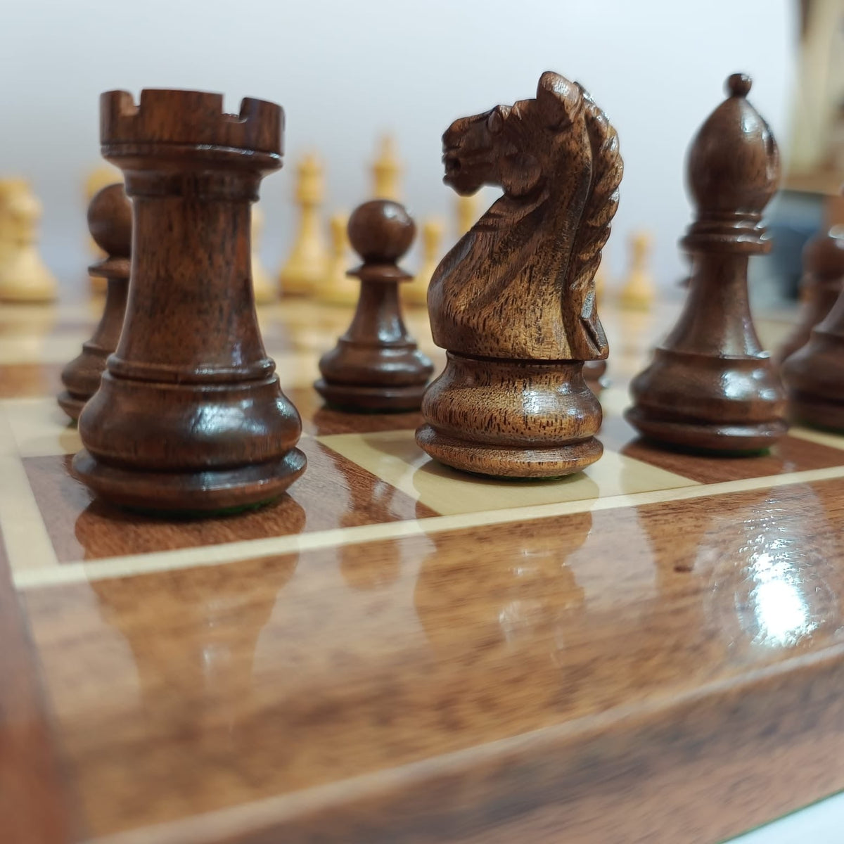 Close-up of Supreme Fierce Knight Staunton chess pieces on luxury acacia wood chess board.