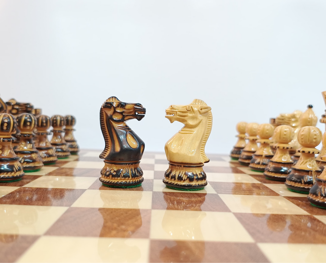 Close-up of hand-carved burnt Staunton wooden chess knights facing each other on a chessboard.